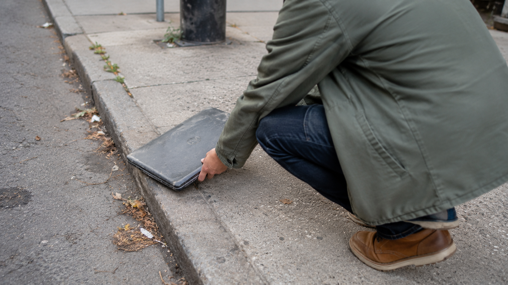 Un laptop abbandonato sul marciapiede accanto al cassonetto